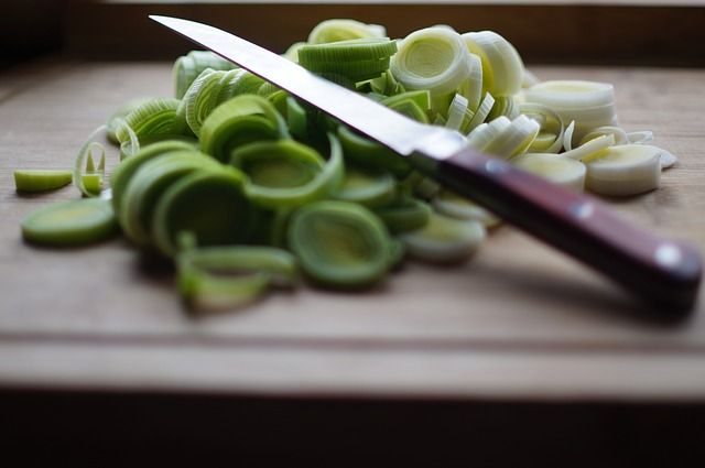 A picture of a knife and chopped onions on a chopping board.